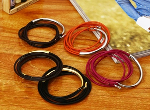 Multi-strand genuine leather wrap bracelet with metallic tubes on wooden surface