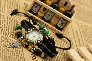 Close-up of retro punk leather bracelet watch with decorative beads and feather charm