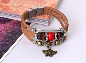 Detail of vintage layered brown leather bracelet with metal beads and bronze butterfly charm