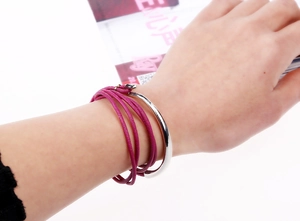 Detail of a multilayer leather wrap bracelet with silver metal cuffs in rose pink