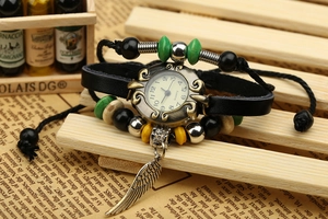 Detail of vintage bohemian leather bracelet watch with bronze dial and feather charm