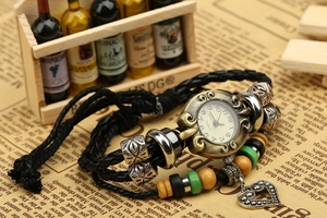 Détail macro d'une montre bracelet en cuir à perles vintage avec breloque cœur sur journal