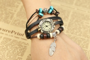 Detailed close-up of a vintage leather layered bracelet watch with beads and silver feather charm