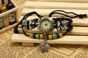 Détail d'une montre bracelet en cuir tressé rétro avec perles et breloque cœur