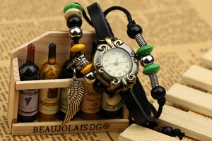 Macro detail of retro quartz watch featuring black leather straps and bronze feather charm