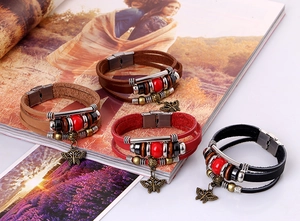 Macro shot showing multi-layer leather bracelets with vintage butterfly charm and steel clasp