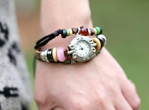 Close-up of vintage leather bracelet watch with colorful beads and carved alloy dial