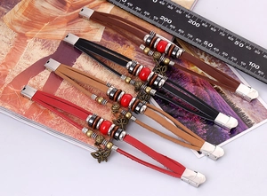 Detail of four bohemian leather bracelets with beads, metal accents, and butterfly charms