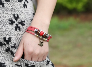 Detail of bohemian red leather beaded bracelet with bronze butterfly charm on wrist