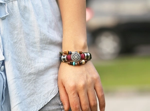 Detail of bohemian leather bracelet with sun pendant, colorful beads and braided cords
