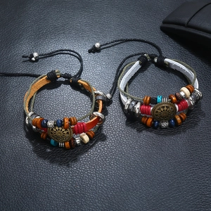 Close-up of multilayer leather beaded bracelets with bronze charms on black background