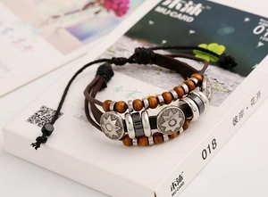 Detail of multi-layer leather braided bracelet with wooden beads and engraved metal charms