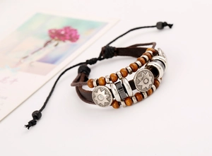 Macro detail of multilayer braided leather bracelet with sun pendant and wooden beads