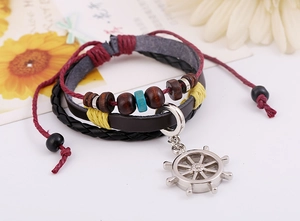 Détail d'un bracelet en cuir multicouche avec perles en bois et breloque gouvernail