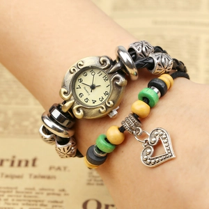 Montre bracelet vintage en cuir perlé avec boîtier bronze et pendentif cœur sur papier