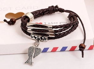 Macro detail of multi-layer braided leather bracelet with silver wing charm and wood beads