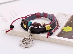 Détail d'un bracelet en cuir multicouche avec pendentif gouvernail argenté et perles bois