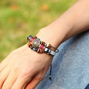Detail of vintage bohemian leather bracelet featuring wooden beads and sun engraved metal charm