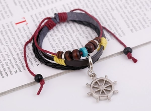 Détail d'un bracelet multicouche en cuir avec perles en bois et breloque gouvernail