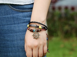 Gros plan du bracelet multicouche en cuir avec perles en bois et pendentif gouvernail