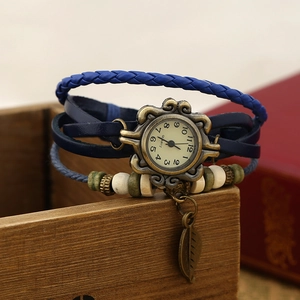 Detailed macro view of vintage layered blue leather strap watch with bronze leaf charm