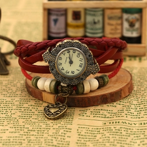 Detail of a vintage red leather wrap watch with heart pendant and wooden beads