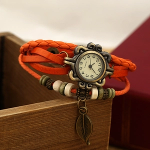 Detail view of woven orange leather strap watch with bronze leaf charm and striped beads