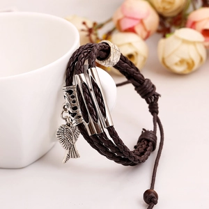 Brown braided leather multi-layer bracelet with angel wing pendant on a white cup