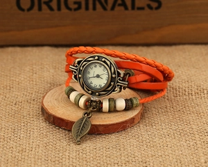 Macro view of vintage braided leather watch with bronze leaf charm and wooden beads