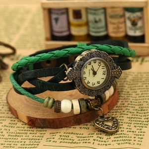 Close-up of vintage multi-layer woven quartz watch with emerald green cords and bronze heart