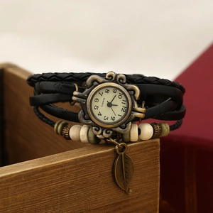 Detailed macro of vintage leather wrap watch with wooden beads and bronze leaf charm