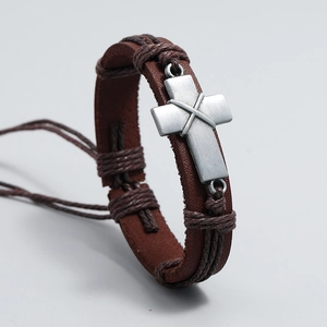 Retro braided leather bracelet with a matte metal cross charm on a grey background