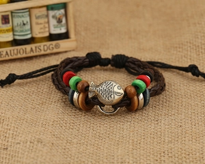 Detail of silver fish charm and colorful wooden beads on brown braided leather bracelet