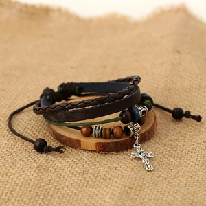 Detail of multilayer leather bracelet with wooden beads and a silver cross pendant