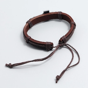 Detailed macro view of woven brown leather bracelet with an antique silver metal cross
