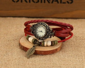 Detail of vintage hand-woven leather watch with bronze leaf pendant and ceramic beads