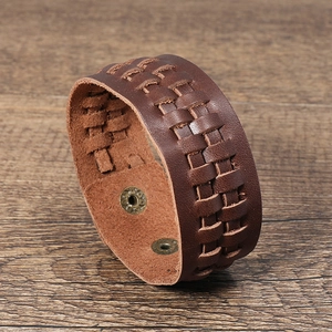 Bracelet tressé en cuir marron vintage avec boucles métalliques sur fond de bois