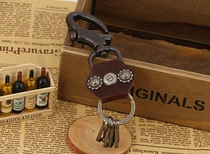 Close-up of vintage brown leather keychain with bronze rivets and spring hook