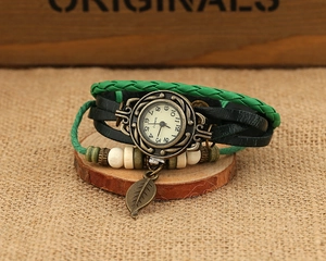 Detail of vintage woven leather watch with wooden beads and bronze leaf pendant