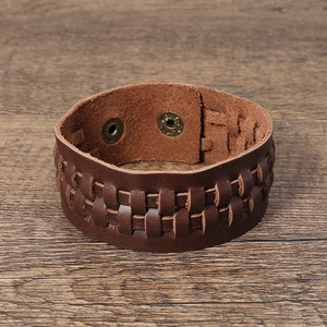 Détail macro du bracelet en cuir tressé marron foncé avec boutons-pression en bronze