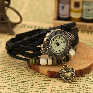 Detail of vintage woven leather watch with bronze heart charm and wooden beads