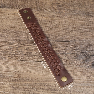Détail d'un bracelet en cuir tressé marron de 23cm avec des boutons pression dorés