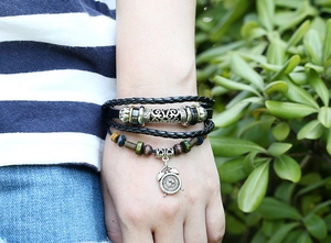 Detail of multi-layer leather bracelet with wooden beads and alarm clock charm