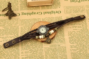 Detail of vintage leather braided watch with ceramic beads and heart pendant on bronze case