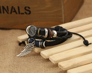 Dettaglio di bracciale punk multistrato in pelle con ala d'argento e perline di bronzo
