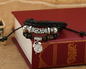 Detail of vintage layered leather bracelet with alarm clock charm on a red book