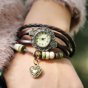 Macro detail of retro leather wrap watch with heart pendant and beaded charms on wrist
