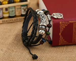 Close-up of punk style multi-layer braided leather bracelet with alarm clock pendant