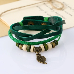 Detail of bohemian multilayer bracelet with green leather straps and bronze leaf pendant