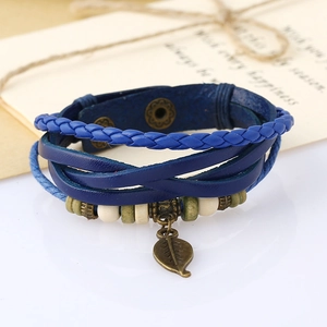 Close-up of woven leather bracelet with wooden beads and bronze leaf pendant
